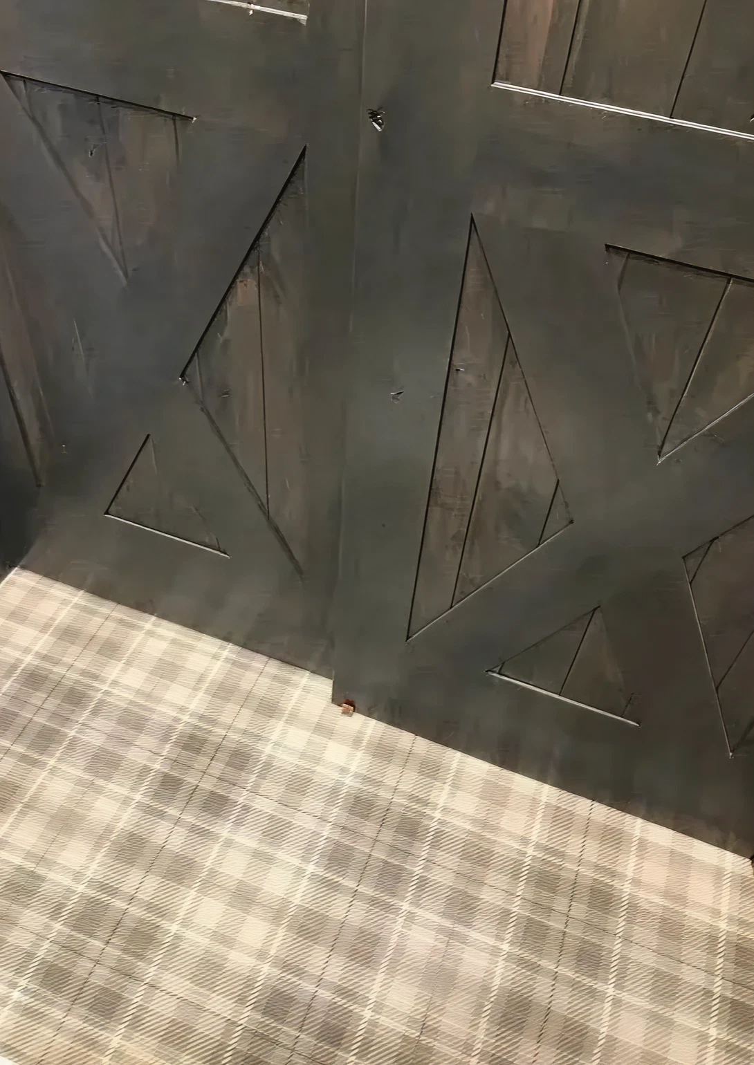 Dark wooden doors with plaid carpet flooring.