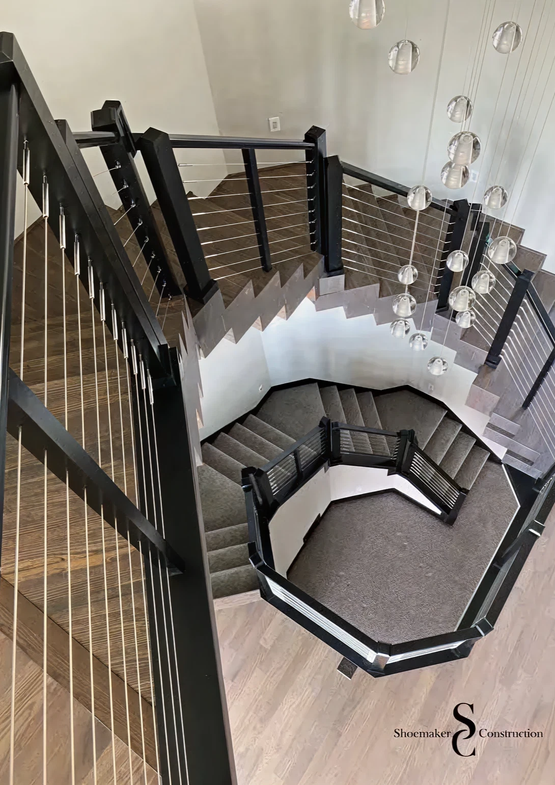 Modern spiral staircase with hanging lights.